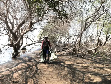 Nelayan membawa kantung berisi tumpahan limbah minyak (oil spill) yang mencemari Pantai Muara Beting, Muara Gembong, Bekasi, Jawa Barat, Minggu (28/7/2019). Sudah empat hari nelayan Muara Gembong beralih profesi menjadi pengepul oil spill yang mencemari pantai. (merdeka.com/Iqbal Nugroho)