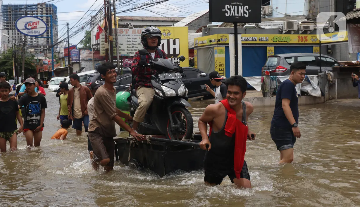 Pengendara sepeda motor melintasi banjir dengan menaiki ojek gerobak di Ciledug, Tangerang, Banten, Kamis (2/1/2020). Jasa ojek gerobak menjadi alternatif bagi warga untuk melintasi banjir. (Liputan6.com/Angga Yuniar)