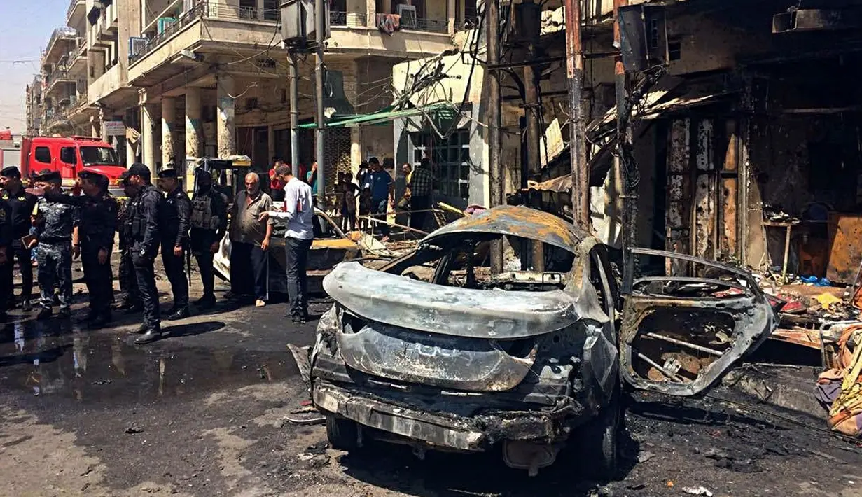 Pasukan keamanan Irak dan warga sipil memeriksa lokasi serangan bom di Baghdad, Irak (30/5). Serangan bom ini sedikitnya telah menewaskan 13 orang dan melukai 24 lainnya. (AP Photo / Karim Kadim)