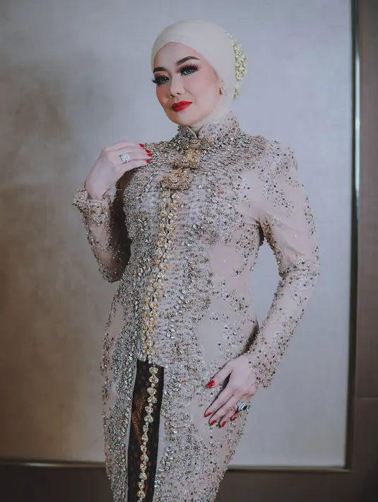 Reza Artamevia mengenakan kebaya panjang berkerah tinggi cokelat dipadukan dengan kain Batik [@rezaartameviaofficial]