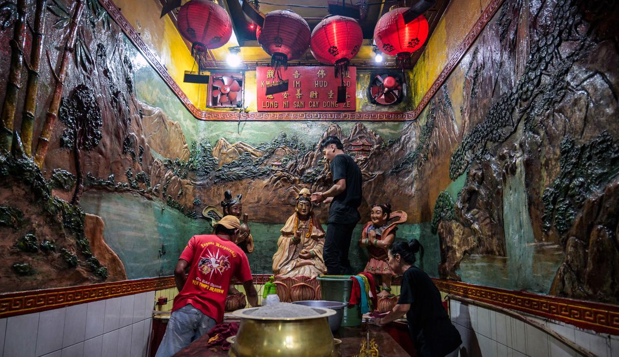 Para sukarelawan membersihkan patung-patung dewa di Kuil Hong San Ko Tee, Surabaya, Jawa Timur, pada Rabu 11 Februari 2026. (JUNI KRISWANTO/AFP)