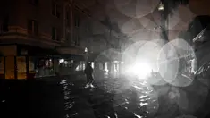 Seorang pria berjalan melewati jalanan yang tergenang air setelah Badai Milton mendarat di Fort Myers, Florida, pada tanggal 9 Oktober 2024. (CHANDAN KHANNA/AFP)