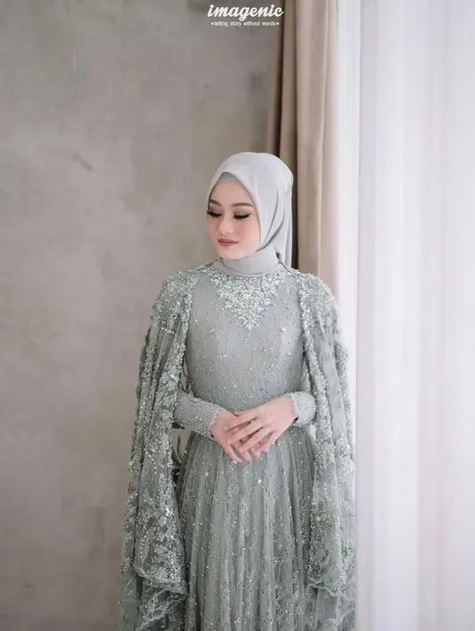 Di momen lamaran, aktris cantik ini mengenakan long dress dengan aksen full brokat dan lengan cape. Untuk hijab, Dinda memilih segi empat yang diikat simple ke belakang. (Instagram/imagenic).