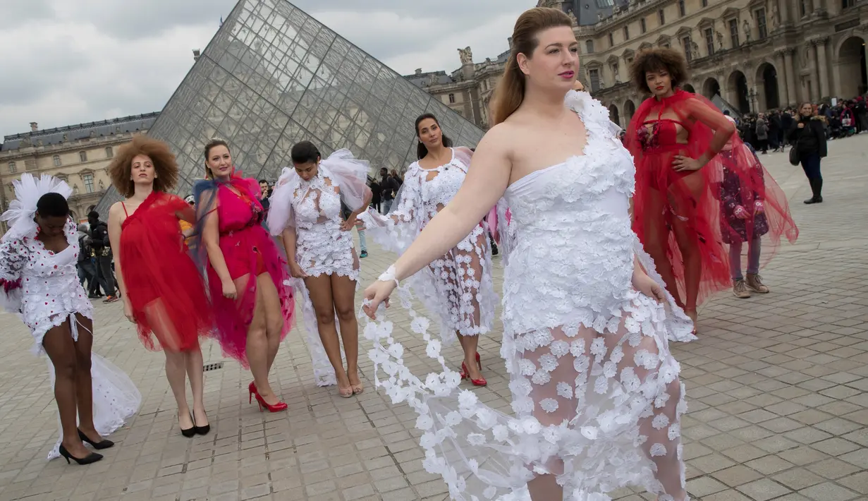 Seorang model ukuran plus berpose di depan piramida Louvre di Paris, Prancis (4/1). Mereka tampil di ruang publik dengan menggunakan busana layaknya di sebuah acara fashion show. (AFP/Thomas Samson)