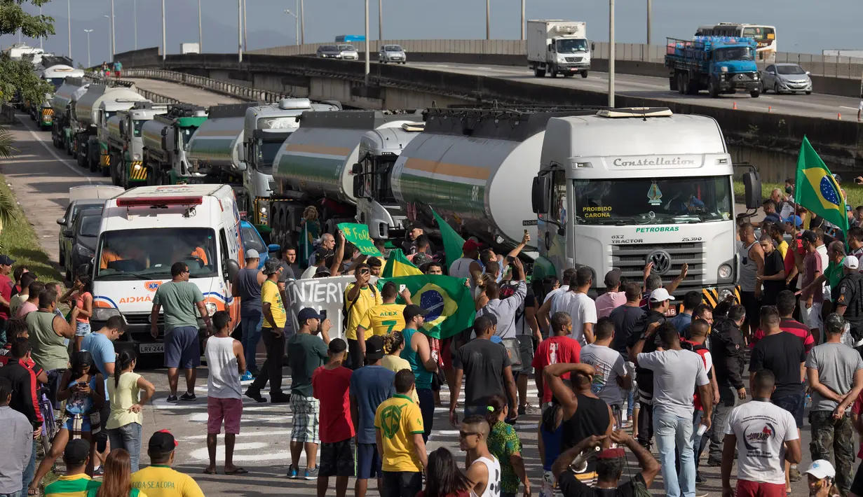 Demonstran menghentikan truk bahan bakar yang tiba untuk mengisi ulang di fasilitas distribusi bahan bakar di Duque Caxias, Brasil, Senin (28/5). Harga BBM dilaporkan terus merangkak naik sejak awal tahun ini. (AP Photo/Leo Correa)