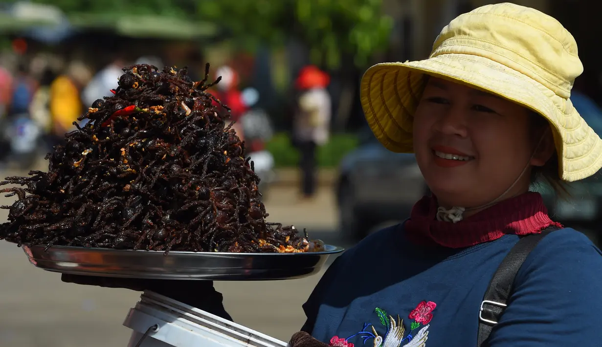 Pedagang Kamboja menjajakan tarantula goreng dan serangga di wilayah Skun, Provinsi Kampong Cham, 4 Desember 2019. Daerah yang kerap dijuluki "Spiderville" tersebut menjadi tempat menarik bagi para turis berburu aping, camilan tradisional dari tarantula ini. (TANG CHHIN Sothy / AFP)