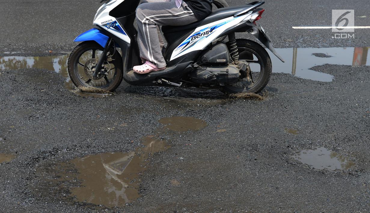 Pengendara mobil dan sepeda motor menghindari jalan yang ruas saat melintasi ruas Jalan Lapangan Ros, Tebet, Jakarta, Sabtu (11/5/2019). Jalan-jalan berlubang yang terisi air tersebut dapat mengakibatkan kecelakaan bagi pengendara kendaraan bermotor. (merdeka.com/Imam Buhori)