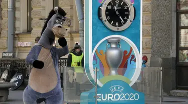 Seorang penampil berkostum kuda berjalan dekat layar hitung mundur Piala Eropa 2020 di St. Petersburg, Rusia, Selasa (17/3/2020). UEFA resmi menunda Piala Eropa 2020 hingga tahun depan. (AP Photo/Dmitri Lovetsky)
