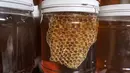 <p>Gambar ini diambil pada 9 Mei 2022 menunjukkan toples madu yang baru dikumpulkan di sebuah peternakan lebah di Khan Yunis di Jalur Gaza selatan. Beberapa peternak juga memanfaatkan lebah untuk terapi kesehatan melalui sengatannya. (SAID KHATIB / AFP)</p>