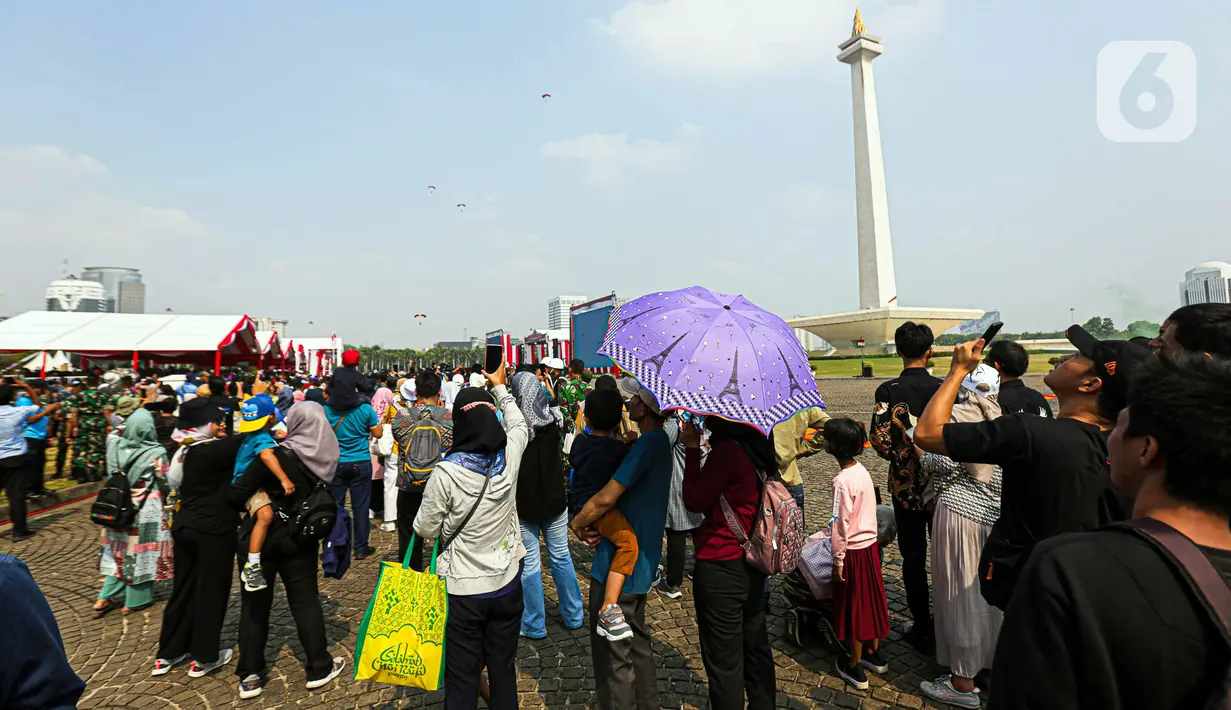 Masyarakat yang hadir tampak senang menyaksikan atraksi terjun payung hingga pesawat tempur. Beberapa dari mereka bahkan tak lepas dari ponselnya untuk mengabadikan setiap momen atraksi yang ditampilkan. (Liputan6.com/Faizal Fanani)
