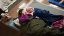 Saat terjadi serangan Rusia, ribuan warga Kyiv, termasuk ratusan anak-anak, berlindung di peron stasiun metro. Tampak dalam foto, seorang wanita dan seorang anak berlindung di stasiun metro selama serangan udara Rusia di Kyiv, pada Selasa 3 Februari 2026 pagi waktu setempat. (Serhii Okunev/AFP)