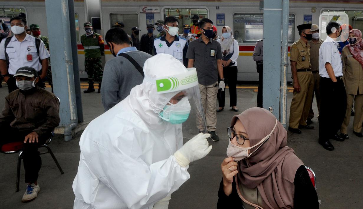 Penumpang KRL Commuter Line diperiksa suhu tubuh saat tes swab di Stasiun Bojonggeder, Jawa Barat, Senin (11/05/2020).  Tes swab dan rapid dilakaukan sebagai salah satu metode untuk mendeteksi dan mencegah penyebaran Covid-19 di moda transportasi KRL Commuter Line. (merdeka.com/Arie Basuki)
