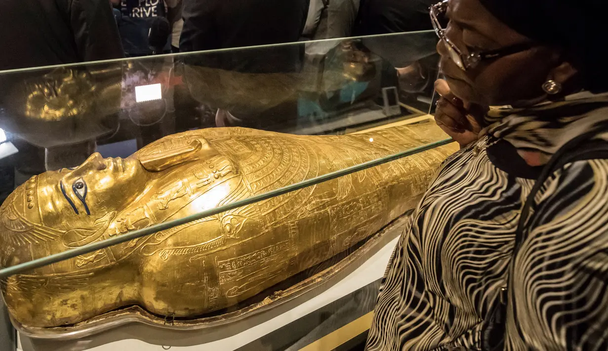 Seorang wanita memperhatikan peti mati emas mumi Nedjemankh yang dipajang di Museum Nasional Peradaban Mesir, Kairo, Selasa (1/10/2019). Nedjemankh merupakan seorang imam di zaman Ptolemeus, sekitar 2.000 tahun lalu. (Khaled DESOUKI/AFP)
