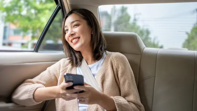 perempuan membawa ponsel tersenyum naik taksi