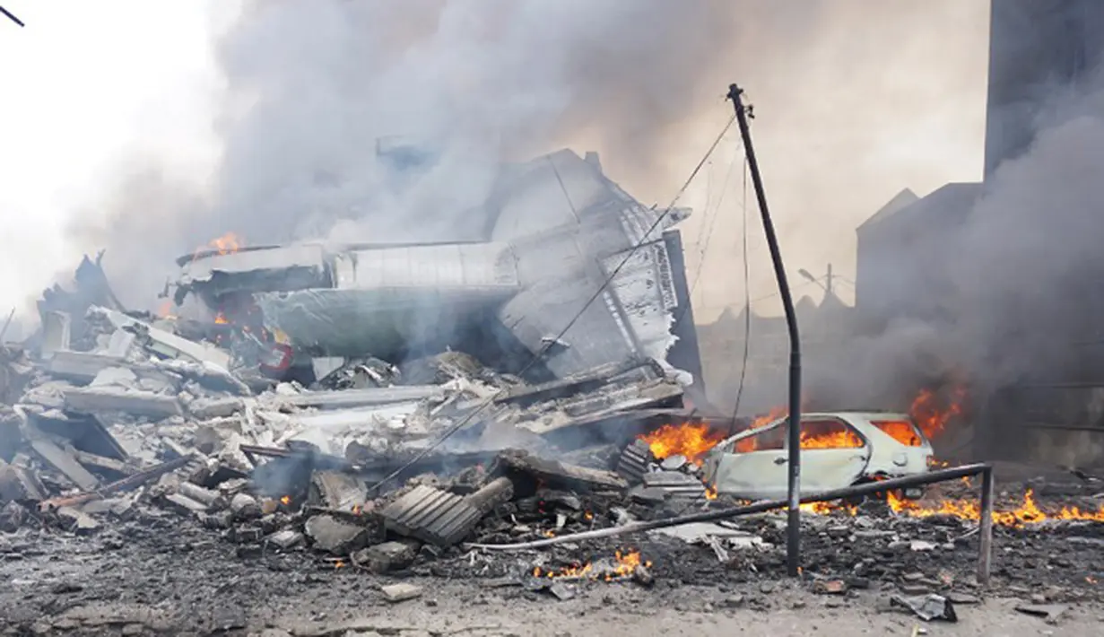 Bagian ekor pesawat Hercules C-130 hangus di tengah rumah rusak dan mobil di kawasan perumahan Medan, Selasa (30/6/2015). Diperkirakan sekitar 50 penumpang berada dalam pesawat untuk melakukan rotasi tugas piket. (AFP PHOTO/Muhammad Zulfan Dalimunthe)