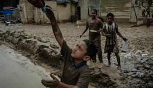 Sebagai informasi, hingga Selasa 16 Desember 2025, Kabupaten Aceh Tamiang masih berada dalam fase pemulihan setelah dihantam banjir bandang pada akhir November 2025 lalu. Tampak dalam foto, seorang anak menerima uang kertas dari seseorang di truk distribusi di Babo, Aceh Tamiang, pada Senin 15 Desember 2025. (Yasuyoshi CHIBA/AFP)