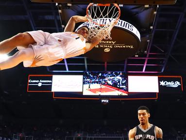 Pemain Phoenix Suns, Devin Booker bergantungan pada ring basket usai melakukan dunks saat melawan San Antonio Spurs pada laga NBA di Talking Stick Resort Arena, (15/12/2016). Spurs menang 107-92. (Reuters/Mark J. Rebilas-USA TODAY Sports)