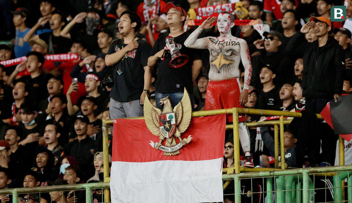 Suporter menyanyikan lagu kebangasaan Indonesia Raya saat memberikan dukungan kepada Timnas Indonesia U-19 yang bertanding melawan Myanmar pada laga Piala AFF U-19 2022 di Stadion Patriot Candrabhaga, Bekasi, Minggu (10/7/2022). (Bola.com/M Iqbal Ichsan)