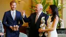 Pangeran Harry dan Meghan Markle menerima hadiah Gubernur Jenderal Australia Sir Peter Cosgrove dalam kunjungan resmi di Sydney, Selasa (16/10). Meghan Markle yang sedang hamil muda tampak senang menerima hadiah bayi pertamanya (Phil Noble/Pool via AP)