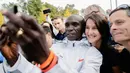Pelari Kenya, Eliud Kipchoge berswafoto dengan penonton saat memenangkan Berlin Marathon ke-45 di Berlin, Jerman, Minggu (16/9). Kipchoge berlari solo di mayoritas lomba, menandakan superioritasnya di atas para pelari lain. (AP Photo/Markus Schreiber)