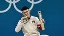 Peraih medali emas dari Indonesia, Rizki Juniansyah, berpose di podium setelah pertandingan angkat besi kelas -73kg putra selama Olimpiade Paris 2024 di South Paris Arena di Paris, pada 8 Agustus 2024. (Miguel MEDINA/AFP)