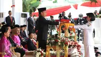 Presiden Jokowi (kiri) menyerahkan bendera Merah Putih kepada anggota Paskibraka Maria Felicia Gunawan saat Upacara Peringatan Detik-detik Proklamasi 17 Agustus di halaman Istana Merdeka, Jakarta, Senin (17/8/2015). (Liputan6.com/Faizal Fanani)