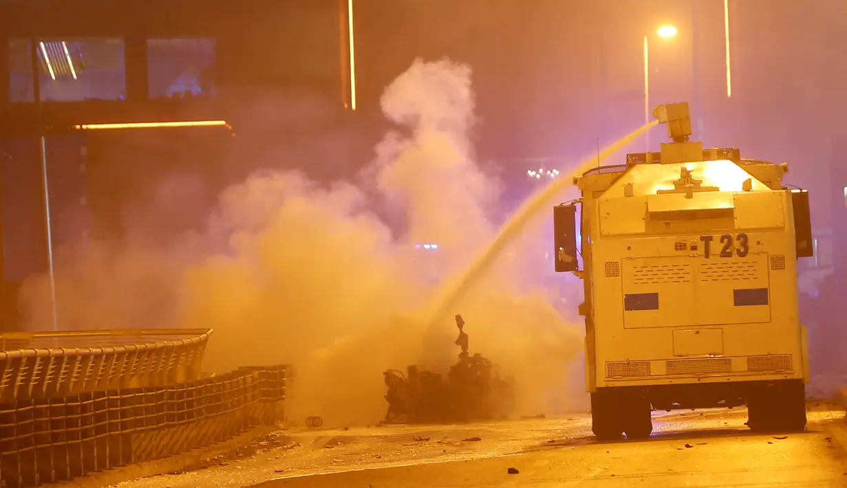 Sebuah mobil meriam air menyemprotkan air untuk memadamkan api sisa ledakan bom di dekat stadion sepak bola di Istanbul, Turki, Sabtu (10/12). Ledakan itu menyebabkan 29 orang tewas, dan melukai 166 orang lainnya. (Reuters/Murad Sezer)