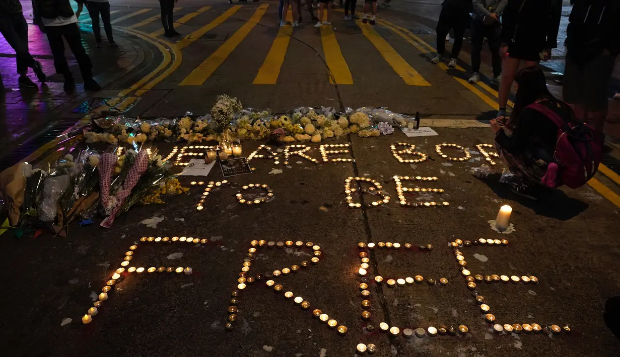 Para pengunjuk rasa menggunakan lilin untuk membentuk kata-kata "Kita dilahirkan untuk bebas" saat memberi penghormatan untuk mahasiswa Alex Chow Tsz-lok yang tewas di Hong Kong (8/11/2019). (AP Photo/Vincent Yu)
