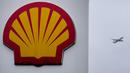Sebuah pesawat terbang melewati tanda di pom bensin shell di London, Kamis (2/2/2023). Shell mencetak laba sebesar US$40 miliar atau setara Rp595,8 miliar pada 2022 di tengah gejolak harga energi setelah invasi Rusia ke Ukraina. (AP Photo/Kirsty Wigglesworth)