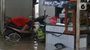 Warga tiduran di atas sepeda motor saat banjir di RW 07, Kelurahan Pekayon, Jakarta Timur, Sabtu (20/2/2021). Banjir di kawasan tersebut terjadi akibat curah hujan yang tinggi. (Liputan6.com/Herman Zakharia)