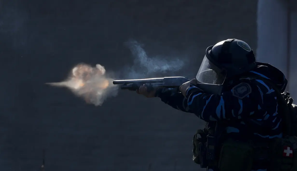 Petugas polisi membidik senjatanya, saat pasukan keamanan menembakkan gas air mata dan peluru karet, selama bentrokan membubarkan kamp penghuni liar dan mengusir orang-orang yang tinggal di sana di Guernica, provinsi Buenos Aires, Argentina (29/10/2020). (AP Photo/Natacha Pisarenko)