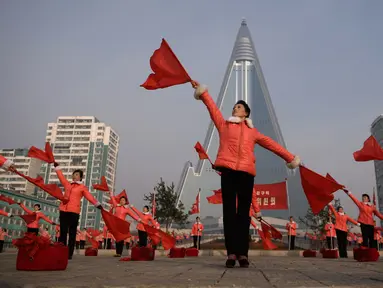 Kelompok Serikat Wanita Sosialis mengibarkan bendera saat melakukan propaganda di depan Hotel Ryugyong, Pyongyang, Korea Utara, Sabtu (9/3). Mereka mengibar-ngibarkan bendera sambil menyanyikan lagu-lagu patriotik selama jam sibuk. (Ed Jones/AFP)