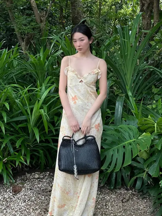 Seulgi juga tampil dengan gaya resortnya, ia mengenakan long dress kuning bermotif spaghetti strap dipadukan handbag hitam motif anyaman. [@hi_sseulgi]