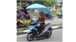 Motornya sih dimodif pakai payung, eh malah si mbak nya enggak pakai helm. (1cak)