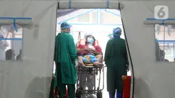 Petugas medis merawat pasien di dalam tenda darurat di depan UGD RSUD Cengkareng, Jakarta Barat, Kamis (24/6/2021). Lonjakan kasus virus corona mengakibatkan ruang IGD penuh, pihak rumah sakit lantas mendirikan tenda darurat untuk merawat pasien covid-19. (merdeka.com/Arie Basuki)