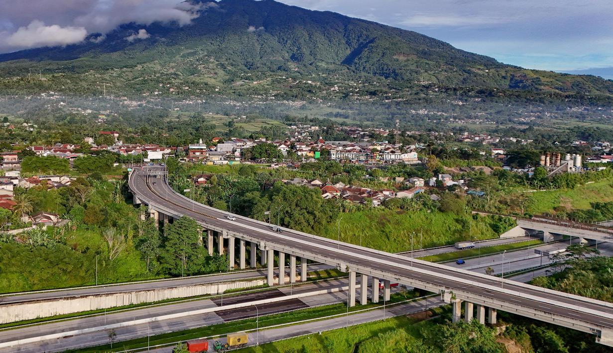 Foto udara memperlihatkan ruas Jalan Tol Bogor-Ciawi-Sukabumi (Bocimi) dengan latar belakang Gunung Salak di Cibadak, Kabupaten Sukabumi, Jawa Barat, Jumat (31/10/2025). Tol Bocimi menjadi infrastruktur penting untuk memperkuat konektivitas wilayah Jawa Barat bagian selatan. (merdeka.com/Arie Basuki)