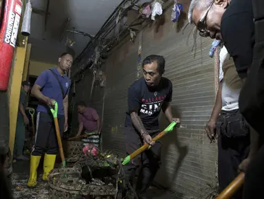 Para pria membersihkan sisa-sisa banjir di Badung, Bali, pada Jumat 12 September 2025. (AP Photo/Firdia Lisnawati)