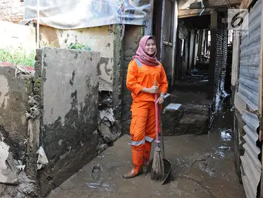 Petugas PPSU Kelurahan Kampung Melayu Siti Hajar berpose saat membersihkan sisa lumpur akibat banjir yang melanda Kebon Pala, Jakarta, Kamis (25/4). Siti Hajar (19) merupakan lulusan SMK yang baru 4 bulan bekerja menjadi pasukan oranye. (Liputan6.com/Herman Zakharia)