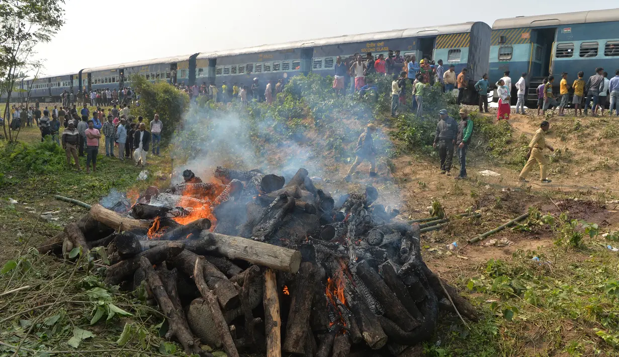 Penumpang menyaksikan tubuh gajah dibakar setelah kereta penumpang yang melaju menabrak dua gajah yang melintasi rel di desa Batasi dekat perbatasan India-Nepal, sekitar 37 km dari Siliguri (11/12/2019). (AFP/Diptendu Dutta)