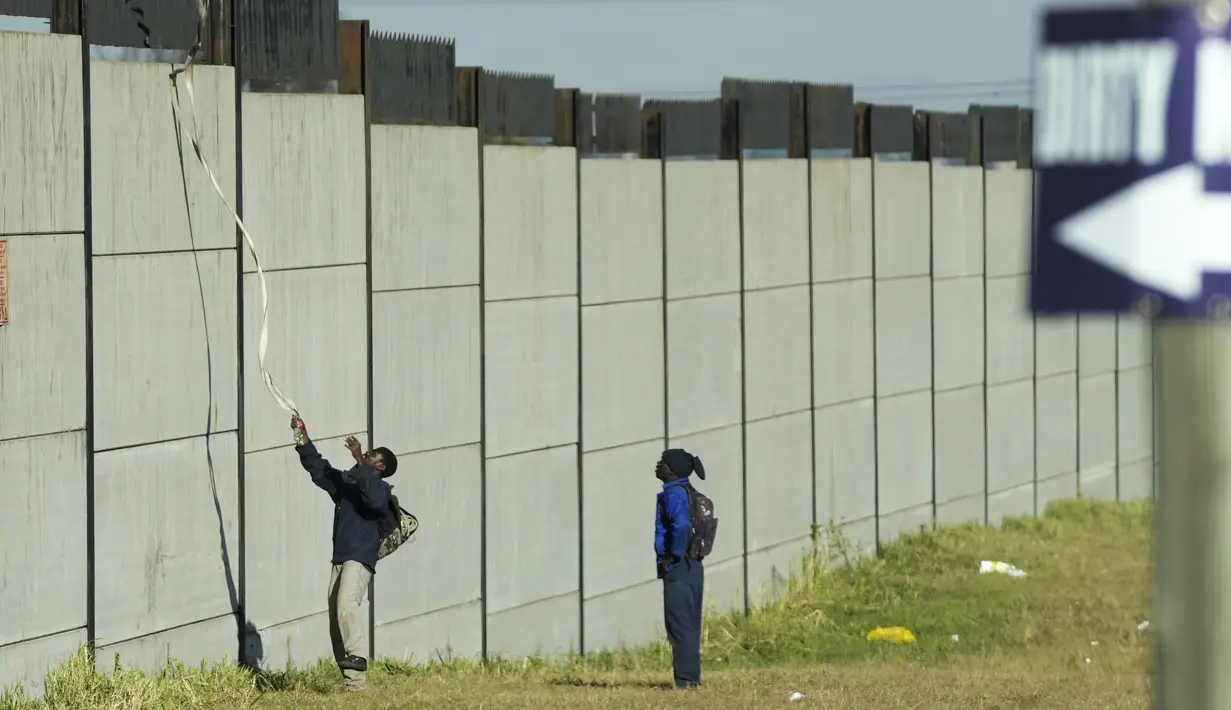 Seorang kolektor besi tua memanjat tembok untuk mencari besi tua untuk didaur ulang di pabrik pengolahan logam di Germiston, timur Johannesburg, Afrika Selatan (30/5/2022). Pengumpul besi tua di area tersebut melompat ke dinding beton untuk mengumpulkan besi tua dan kemudian menjualnya ke toko bekas. (AP Photo/Themba Hadebe)