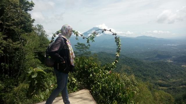 seorang pengunjung berfoto dengan latar pemandangan gunung