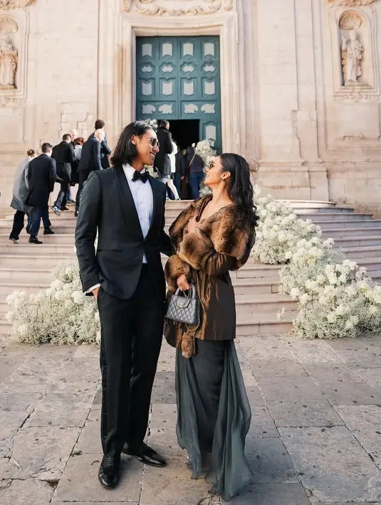 Sean Gelael tampil necis dengan tuxedo hitam yang membuatnya terlihat gagah. Sementara itu, Hana Malasan mengenakan dress berwarna abu-abu yang dipadukan dengan outer cokelat syal bulu, memberikan kesan anggun namun tetap simpel. Penampilan mereka begitu serasi sebagai pasangan kekasih. (Liputan6.com/IG/@gelaelized)