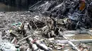 Seorang pria berjalan di atas puing-puing bangunan yang runtuh akibat banjir di Denpasar, Bali, pada Jumat 12 September 2025. (SONNY TUMBELAKA/AFP)