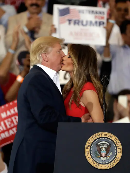 Presiden AS, Donald Trump mencium istrinya, Melania Trump selama reli kampanye di Bandara Internasional Orlando Melbourne, Florida (18/2). Donald Trump terlihat mesra dengan sang istri saat pertemuan tersebut. (Joe Raedle / Getty Images / AFP)