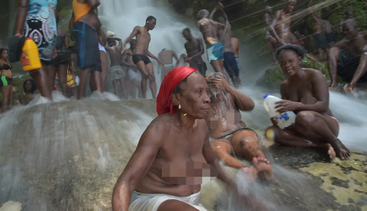 Sejumlah wanita bertelanjang dada mandi di bawah air terjun di Saut d' Eau, Haiti (15/7). Ini merupakan ritual tahunan untuk menyembuhkan penyakit dan mensucikan diri. (AFP Photo/Hektor Retamal)
