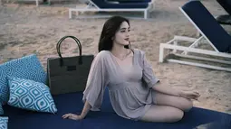 Ranty juga berpose duduk di kursi sambil memandang keindahan pantai. Warna dress yang samar dengan kulit putih cerah Ranty semakin menonjolkan kecantikannya. Potongan v-neck rendah pada busana tersebut memberikan kesan feminin yang memikat. (Liputan6.com/IG/@rantymaria)