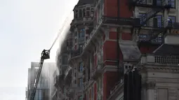 Petugas pemadam kebakaran berusaha menjinakkan kobaran api di hotel Mandarin Oriental, London, Inggris, Rabu (6/6). Laporan menyebutkan kebakaran terjadi di atap hotel bintang lima tersebut. (AFP / Ben STANSALL)