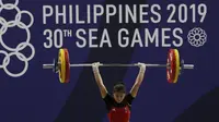 Lifter Aisyah Windy melakukan angkatan saat SEA Games 2019 cabang angkat besi nomor 49 kg di Stadion Rizal Memorial, Manila, Minggu (1/12). Dirinya meraih emas dengan total angkatan 104 kg. (Bola.com/M Iqbal Ichsan)
