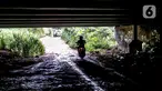 Pengendara sepeda motor melintas di kolong Tol Jagorawi, Cimanggis, Depok, Jawa Barat, Minggu (8/11/2020). Buruknya jalan dan minimnya penerangan membuat akses tersebut rawan aksi kejahatan. (Liputan6.com/Faizal Fanani)