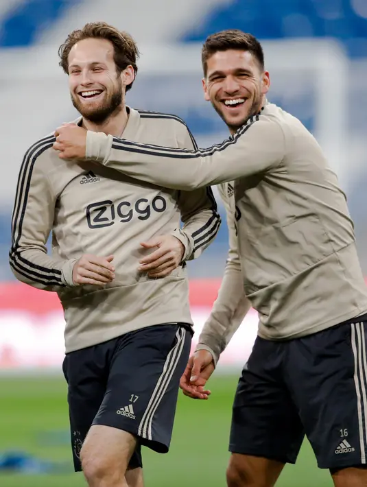 Pemain Ajax Amsterdam Daley Blind (kiri) dan Lisandro Magallan bercanda saat berlatih di Stadion Santiago Bernabeu, Madrid, Spanyol, Senin (4/3). Ajax akan menghadapi Real Madrid pada leg kedua babak 16 besar Liga Champions. (AP Photo/Bernat Armangue)
